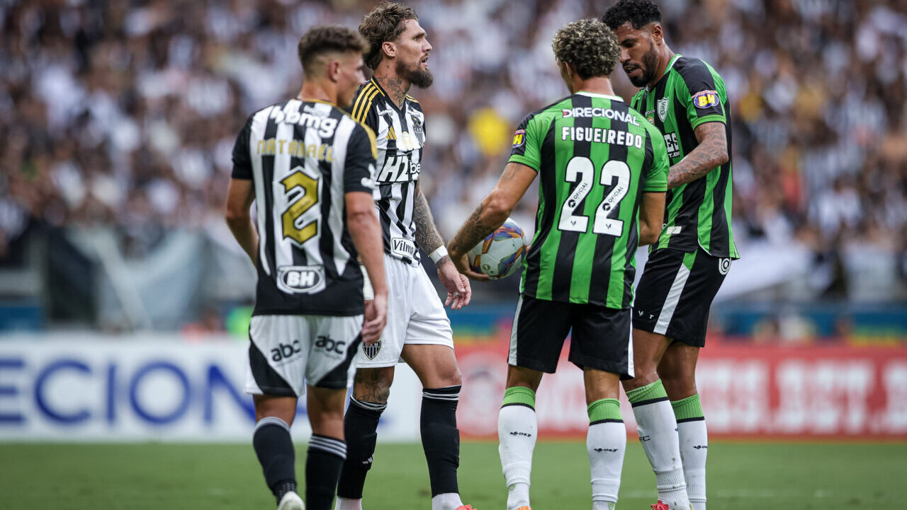 Escudo do Atlético Mineiro em campo durante partida de futebol.
