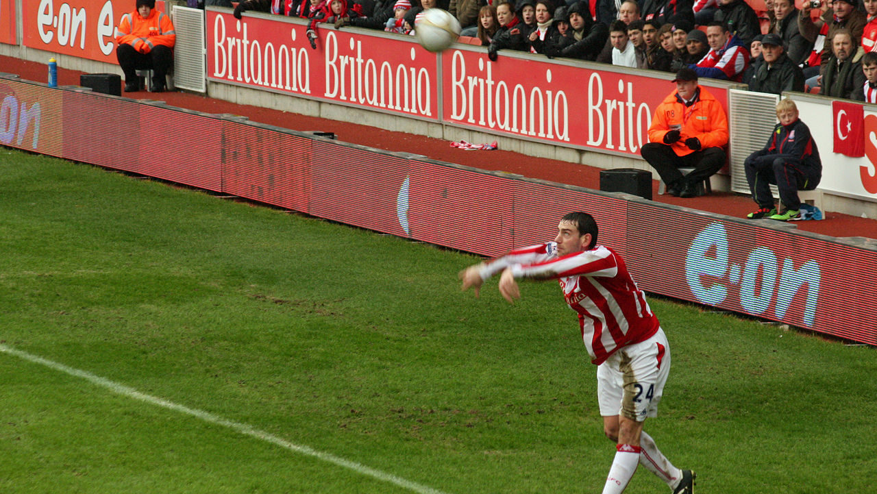 Jogador realizando um lateral longo durante uma partida de futebol
